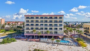 A multi-story hotel with balconies, a pool, and a beachside location.
