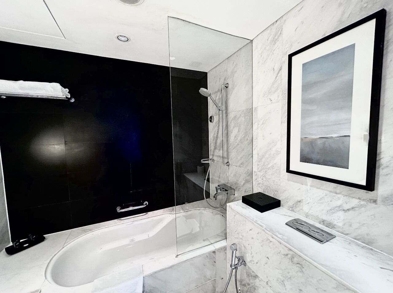 Une salle de bain moderne dotée d’une douche à parois de verre, d’une grande baignoire et d’un comptoir en marbre.
