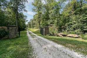 A gravel path leading through a wooded area with stone walls on either side.