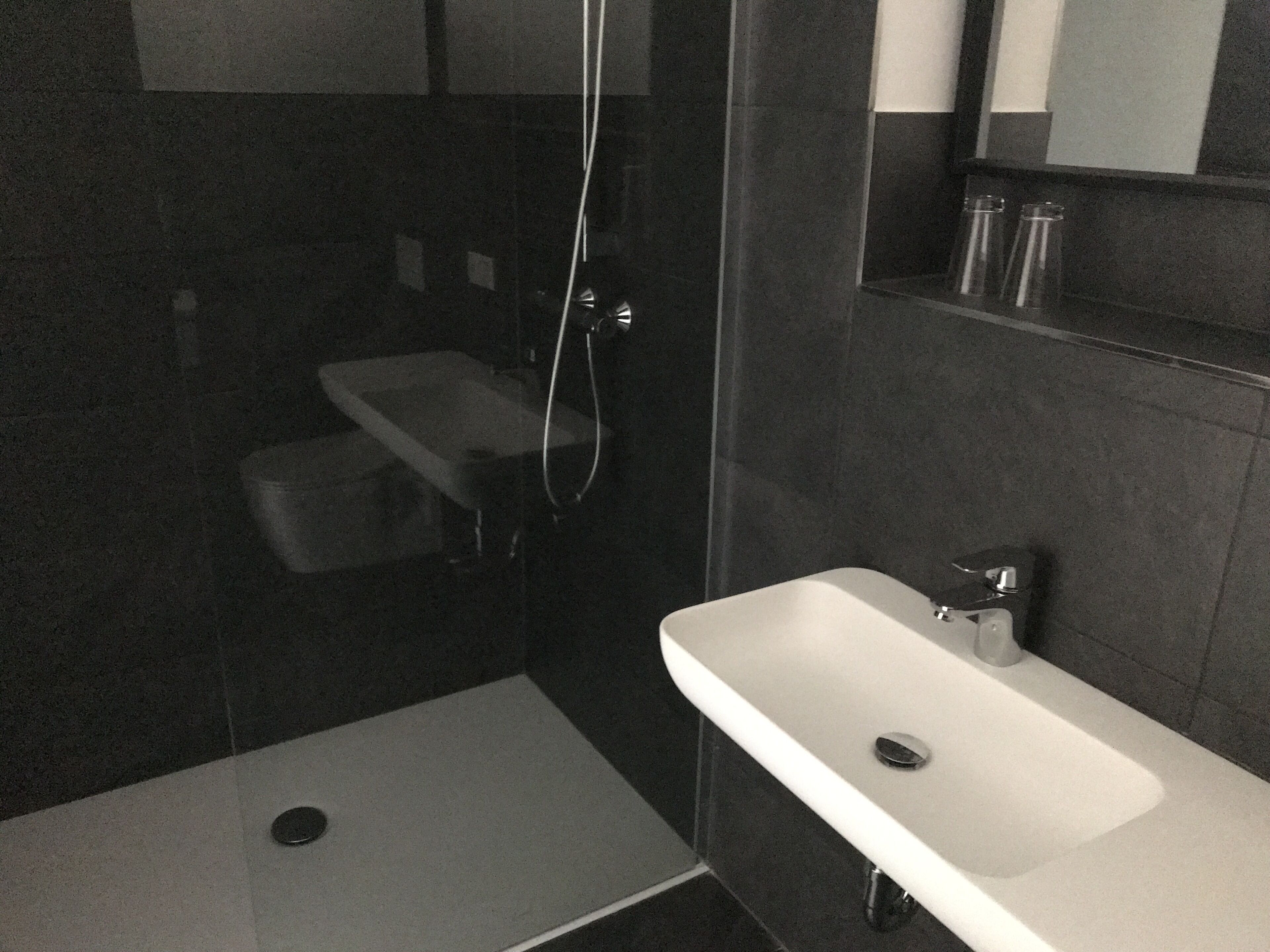 A bathroom with a shower, a sink, and a mirror.
