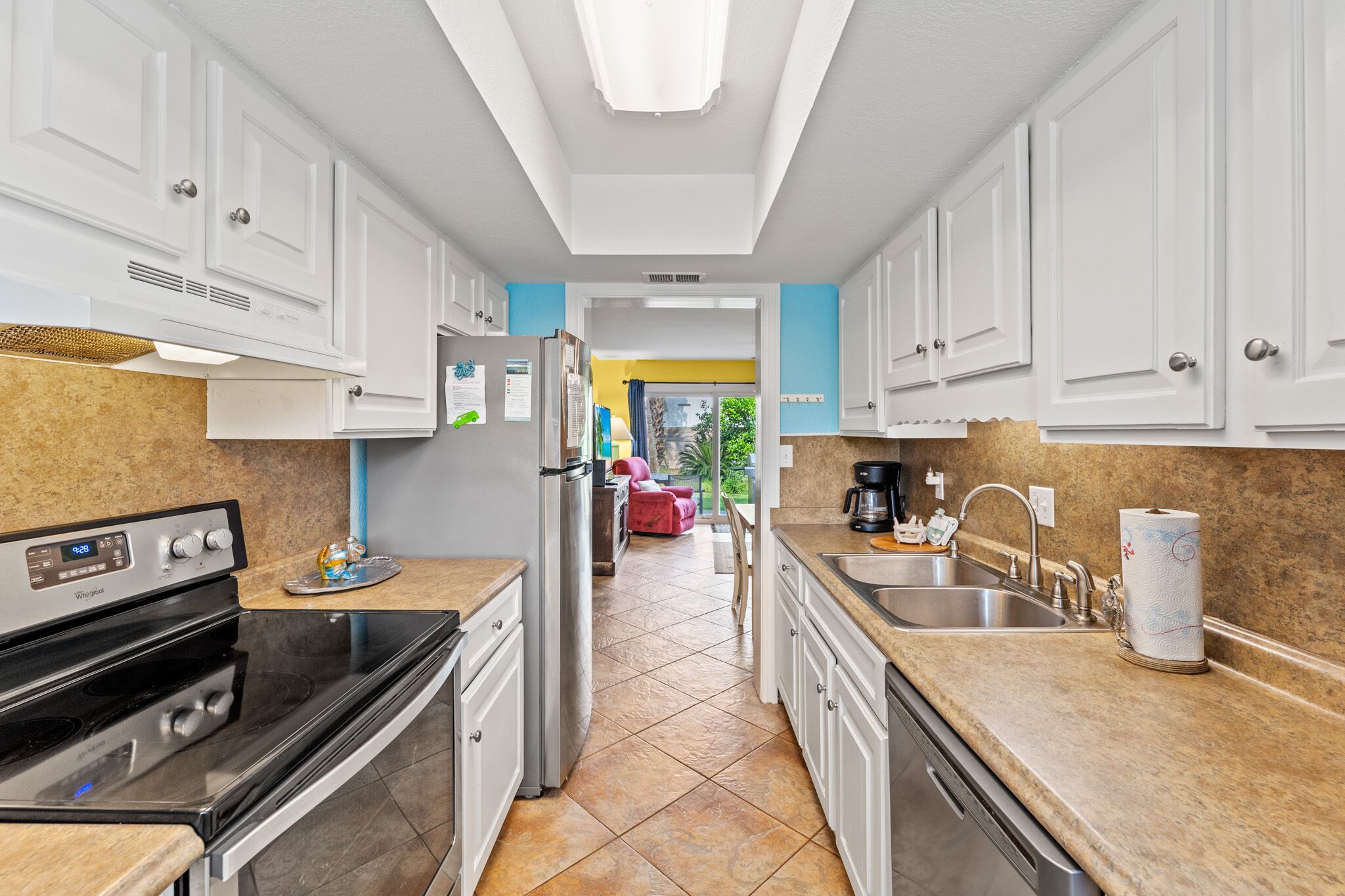 A modern kitchen with white cabinets, a stainless steel refrigerator, a built-in oven, and a granite countertop.