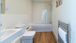 A modern bathroom with a bathtub, toilet, and sink. - Apartment 5 Isabella House Hereford (Hereford)