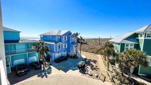 Ein zweistöckiges Haus mit blauer Fassade, einer überdachten Auffahrt und Blick auf den Strand.