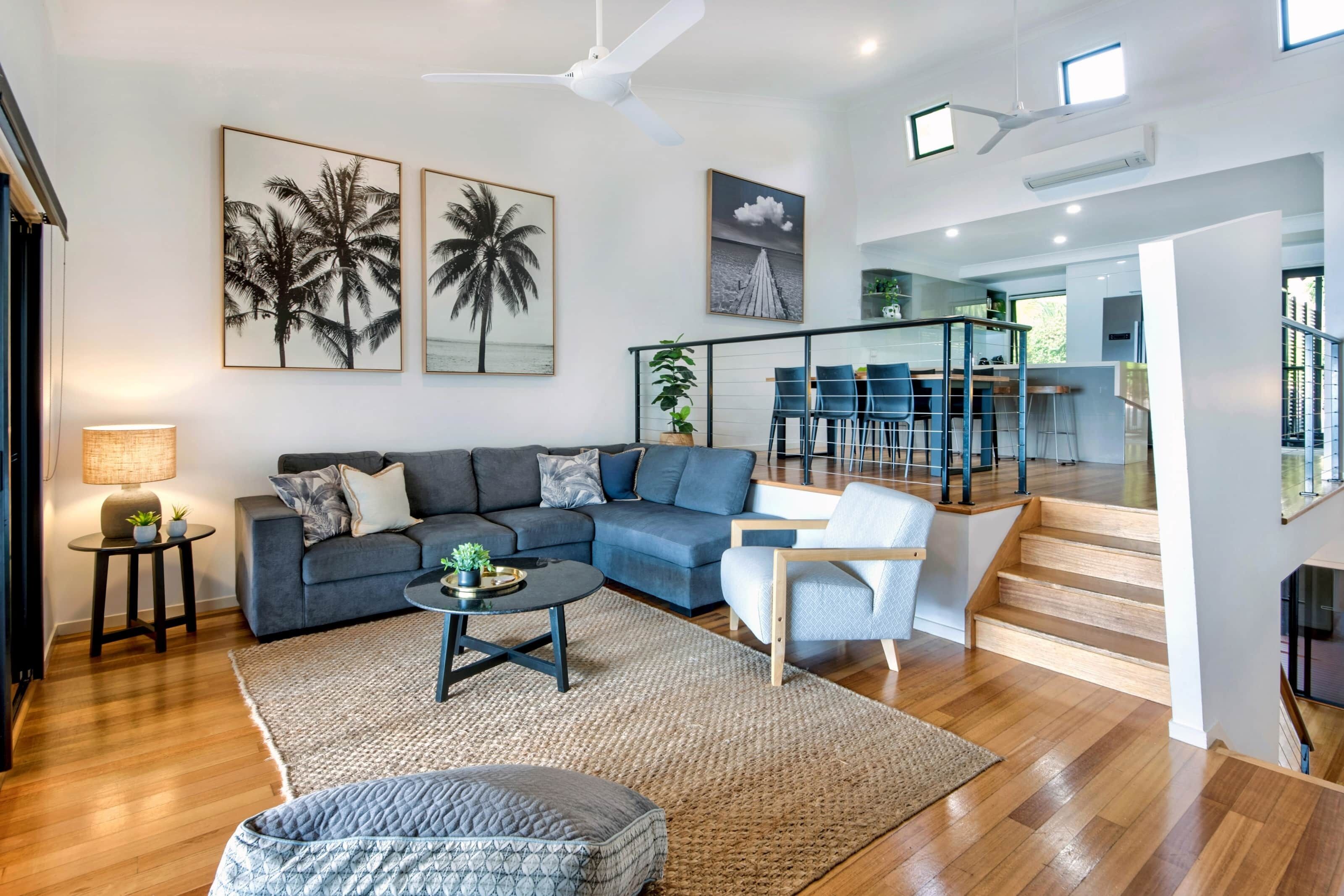 A modern living room with a sofa, coffee table, and a staircase leading to a balcony.