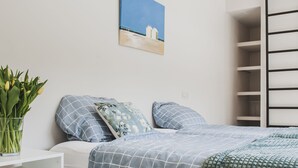 Un dormitorio moderno con una cama, una mesita de noche con un jarrón de flores y un estante en la pared.