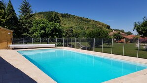 A rectangular swimming pool with a clear blue water surface, surrounded by a tiled deck and a metal fence. - House La Galinette 9 people Heated swimming pool Hammam Jacuzzi Sauna (Izeaux)