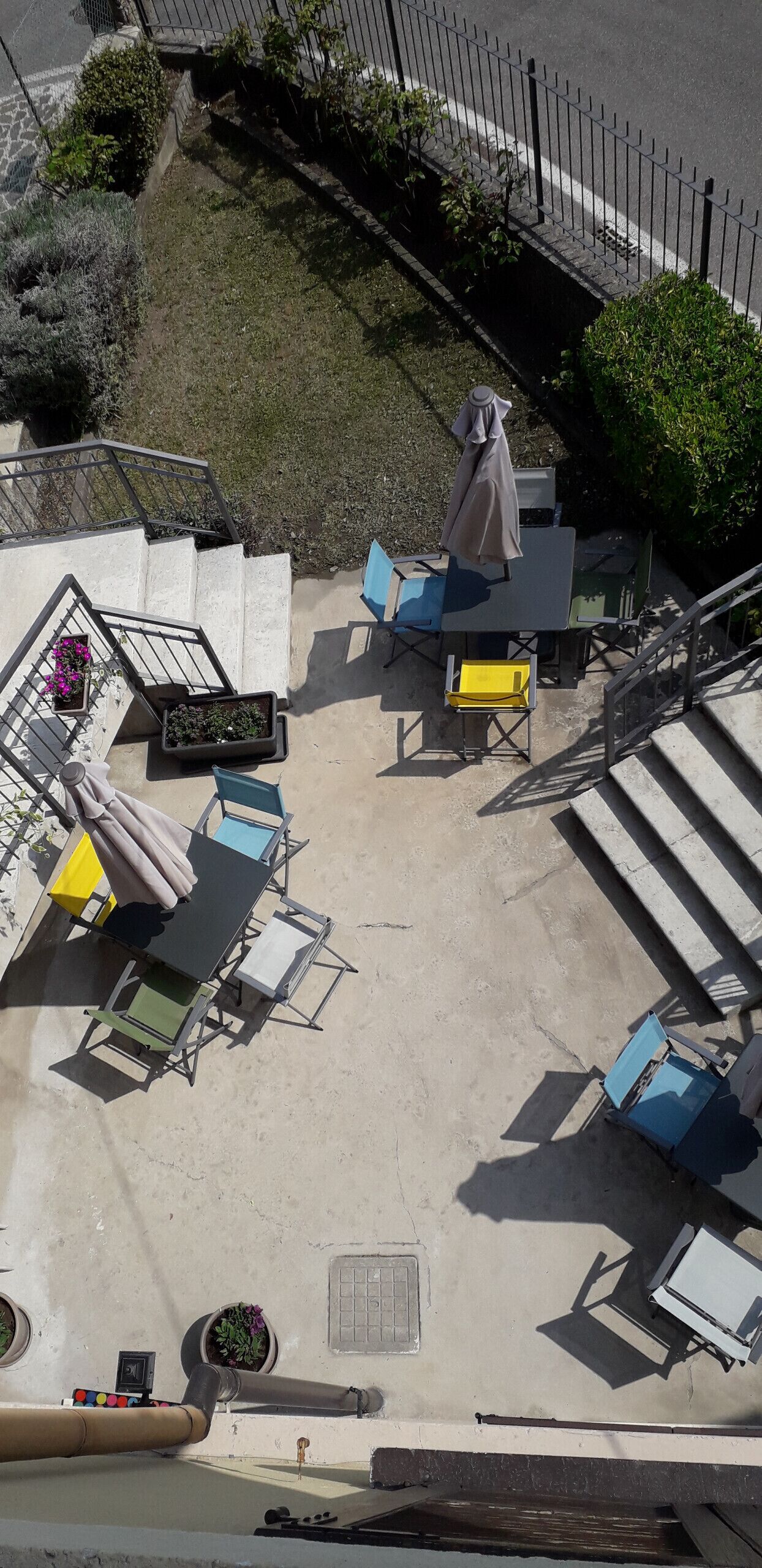 Un espace extérieur aménagé avec une table et des chaises, un banc couvert et un petit jardin agrémenté de plantes en pot.
