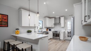 A modern kitchen with white cabinetry, a central island, and bar stools.