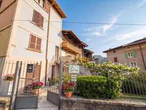 Un bâtiment traditionnel doté d’un balcon, d’une enseigne indiquant la présence d’un restaurant et d’un portail agrémenté de plantes en pot.