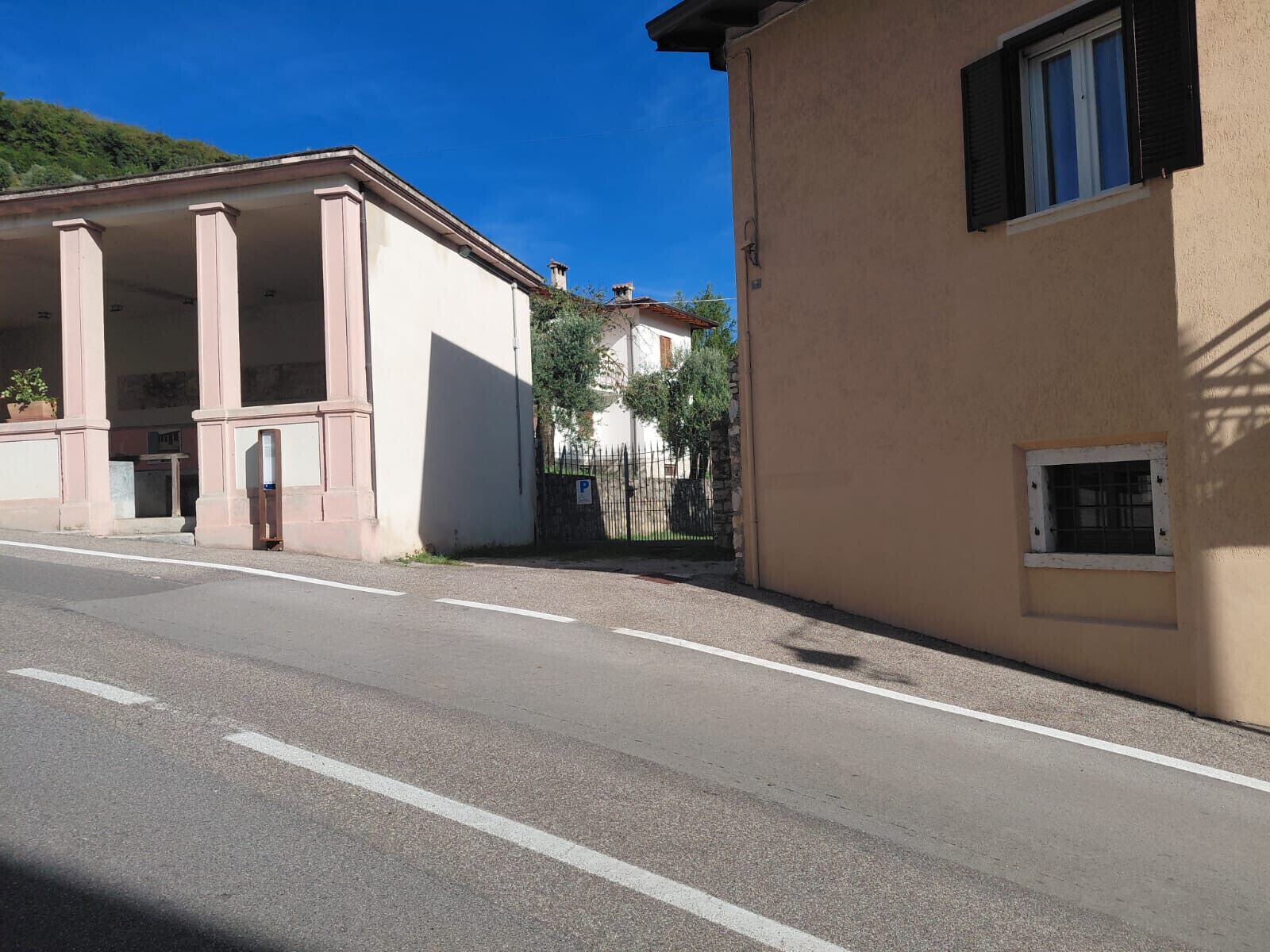 A street with a building featuring a covered entrance and a small window.