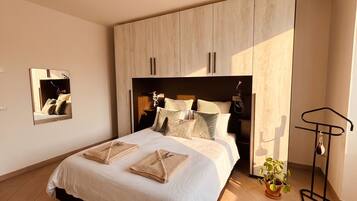 A bedroom with a bed, bedside tables, a mirror, a wardrobe, and a plant.