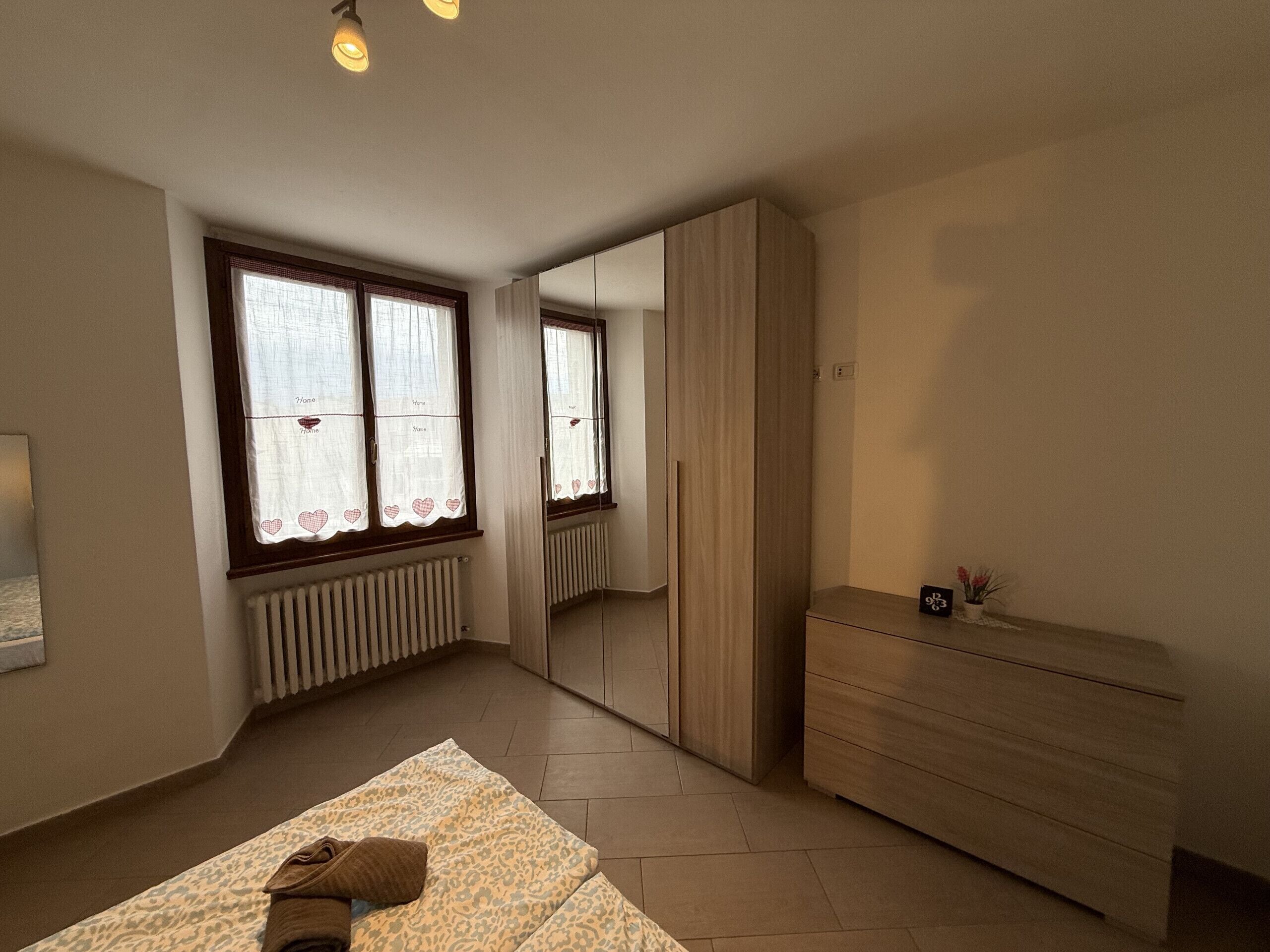 Quarto com cama, penteadeira, espelho e radiador.