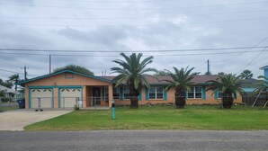 Un bâtiment à deux étages, de couleur beige à l’extérieur, avec des bordures de couleur turquoise, doté d’un porche à l’avant et d’une boîte aux lettres.