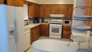 Une cuisine avec des meubles de rangement en bois, un réfrigérateur blanc, une cuisinière et un évier.
