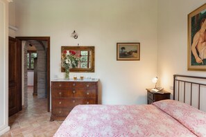 Une chambre à coucher avec un lit, une commode, une coiffeuse et un tableau accroché au mur.