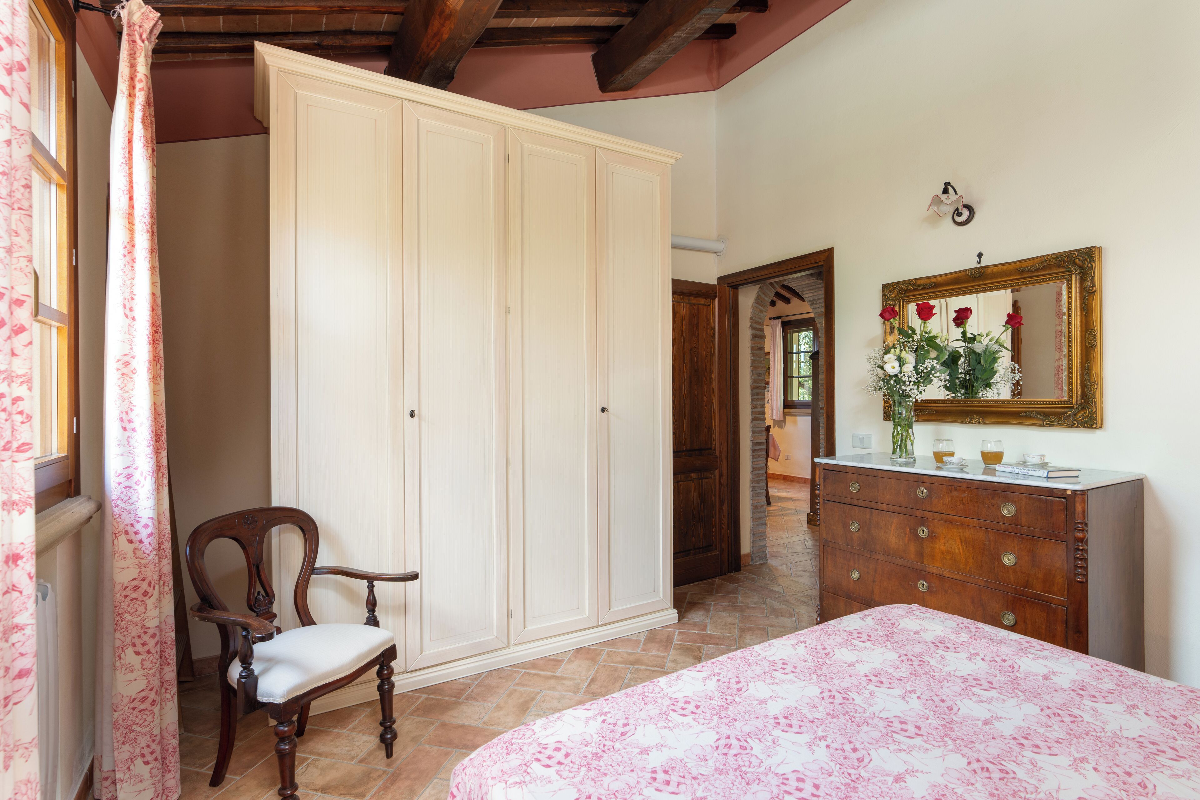 A bedroom with a bed, a wooden chair, a wardrobe, a dresser, and a mirror.