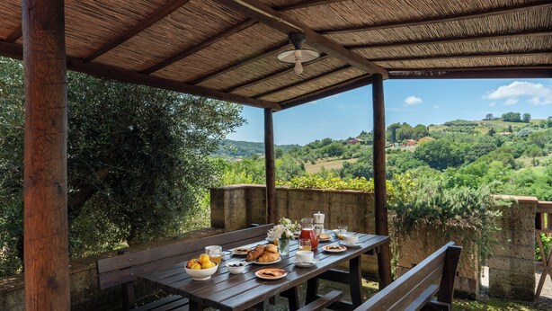 A wooden table set outdoors with a view of a lush landscape. - Villa Riparbella (Riparbella)