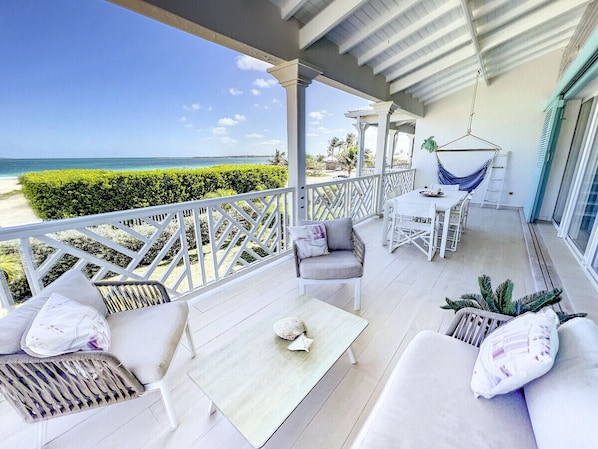 A covered outdoor area with a view of the beach, furnished with white sofas, a table, and chairs. - Princess Anouk, plage, piscine, Wifi ultra rapide (Orient Bay)