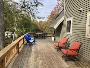 Ett trädäck med utemöbler, en pergola och ett hus med träpanel.