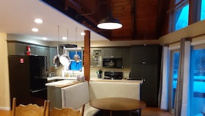 Een moderne keuken met een eethoek, houten plafond en uitzicht op de omgeving.