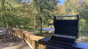 Een houten terras met een barbecue en tuinmeubilair.