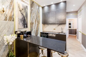 Una cocina moderna con paredes de mármol, una isla central con taburetes y electrodomésticos de acero inoxidable.