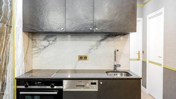 A modern kitchen with a built-in oven, dishwasher, and stainless steel sink.