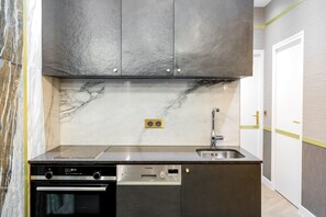 A modern kitchen with a built-in oven, dishwasher, and stainless steel sink. - Merveil - Luxury Suite - Tour Eiffel - Laos (Paris)