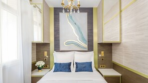A modern bedroom with a large bed, two nightstands, a chandelier, and a wall-mounted abstract painting. - Merveil - Luxury Suite - Tour Eiffel - Laos (Paris)