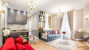 Un salon moderne avec un canapé bleu, des coussins rouges, une table basse et un lustre.