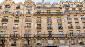 A multi-story building with balconies, large windows, and ornate architectural details. - Merveil - Luxury Suite - Tour Eiffel - Laos (Paris)