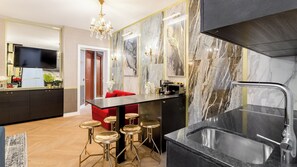 A modern kitchen with a marble backsplash, a black countertop, and a stainless steel sink.
