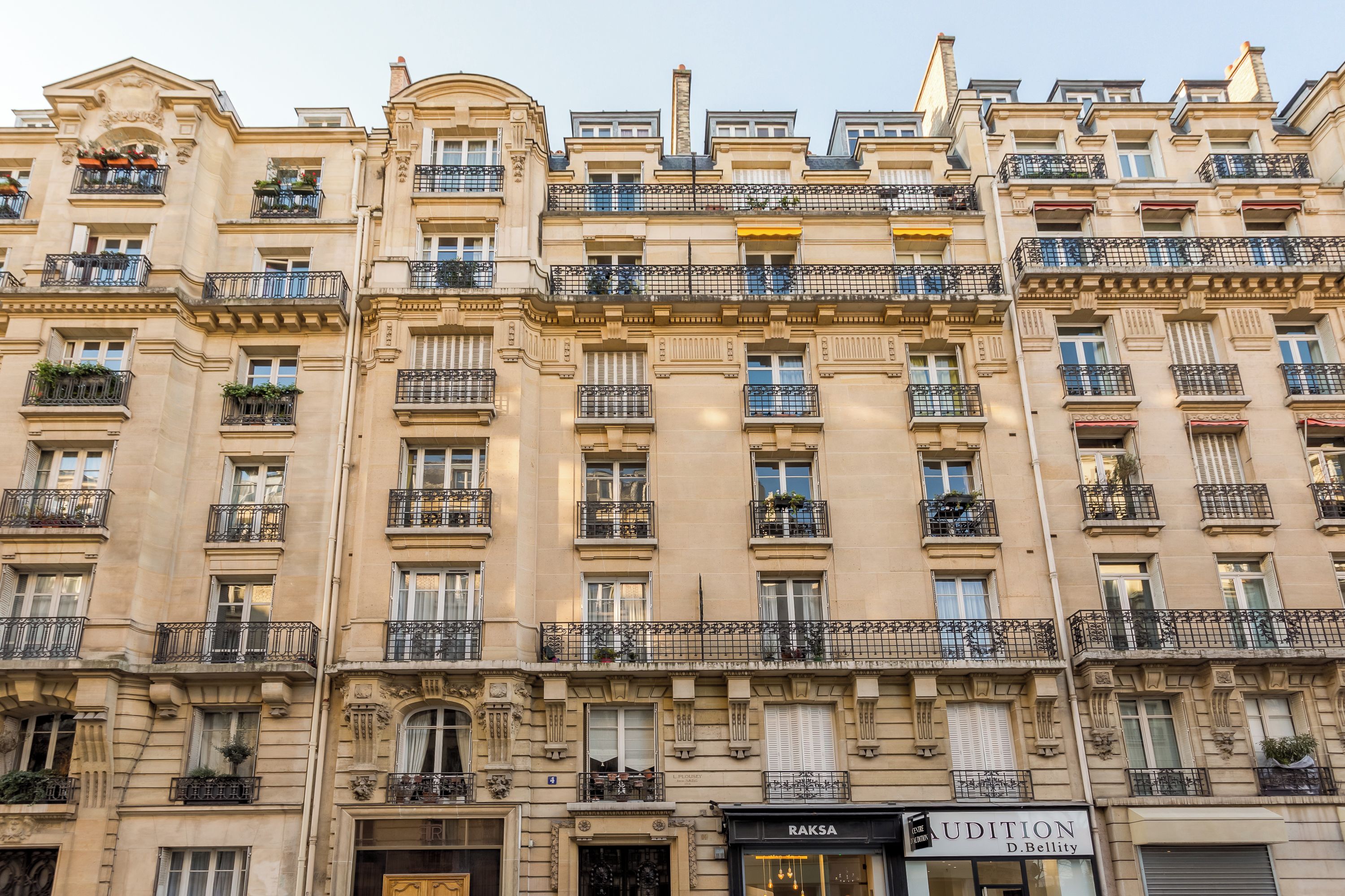 Un edificio a più piani con dettagli architettonici elaborati, tra cui balconi con ringhiere in ferro battuto e modanature decorative.