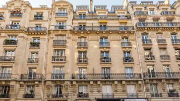 Un edificio a più piani con dettagli architettonici elaborati, tra cui balconi con ringhiere in ferro battuto e modanature decorative.