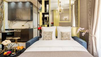 Camera d'albergo moderna con un letto grande, un angolo cottura e un bagno visibile tramite una parete divisoria in vetro.