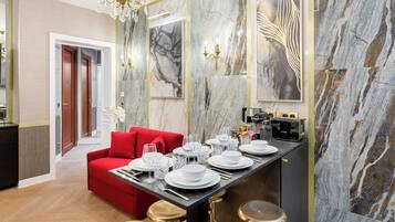 A modern dining area with a red sofa, a marble wall, and a kitchen counter with a Bosch coffee machine.