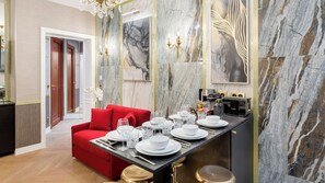 A modern dining area with a red sofa, a marble wall, and a kitchen counter with a Bosch coffee machine. - Merveil - Luxury Suite - Tour Eiffel - Laos (Paris)