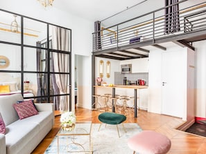 Un apartamento moderno con zona de estar tipo loft, una cocina con isla central y una escalera que lleva a un nivel superior.