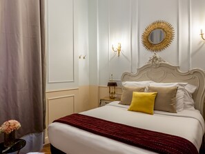 A hotel room with a large bed, a decorative mirror, a nightstand, and a vase with flowers. - Merveil - Luxury Suite - Louvre - Aboukir I (Paris)