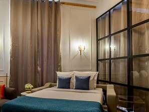 A hotel room with a bed, curtains, a wall-mounted light fixture, and a large window.