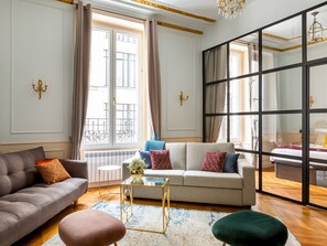 A modern living room with a sofa, ottoman, and a glass coffee table. - Merveil - Luxury Suite - Louvre - Aboukir I (Paris)