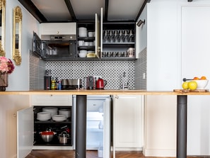 Una cocina con refrigerador incorporado, microondas y cafetera.