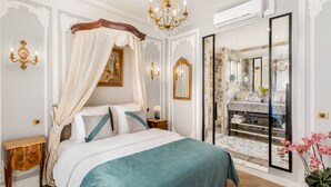 A bedroom with a four-poster bed, a chandelier, and a large mirror. - Merveil - Signature Suite - Louvre - Victoria (Paris)