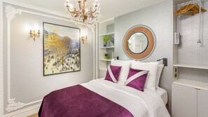 Une chambre à coucher avec un lit, un lustre, un tableau et un miroir.