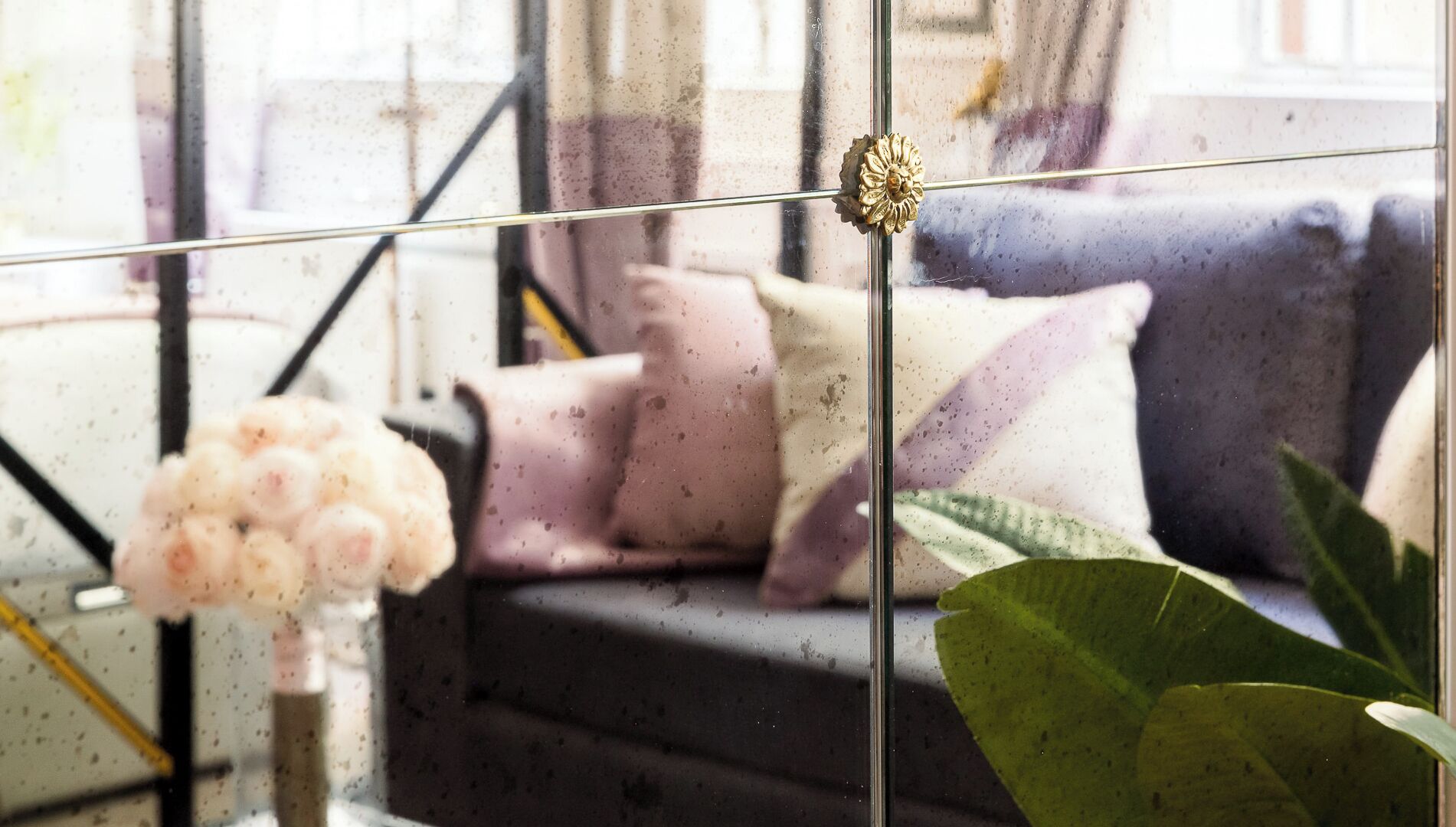 A modern interior with a sofa, cushions, and a plant.