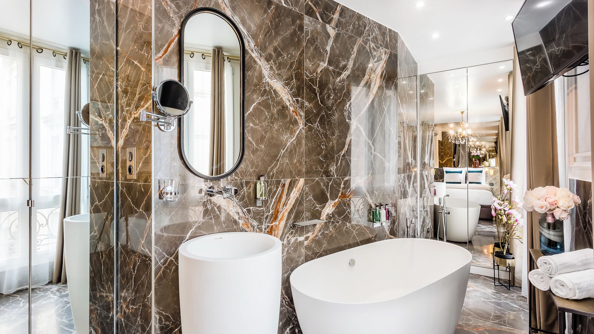 Un bagno lussuoso con due ampi lavandini bianchi, una vasca freestanding e uno specchio grande.