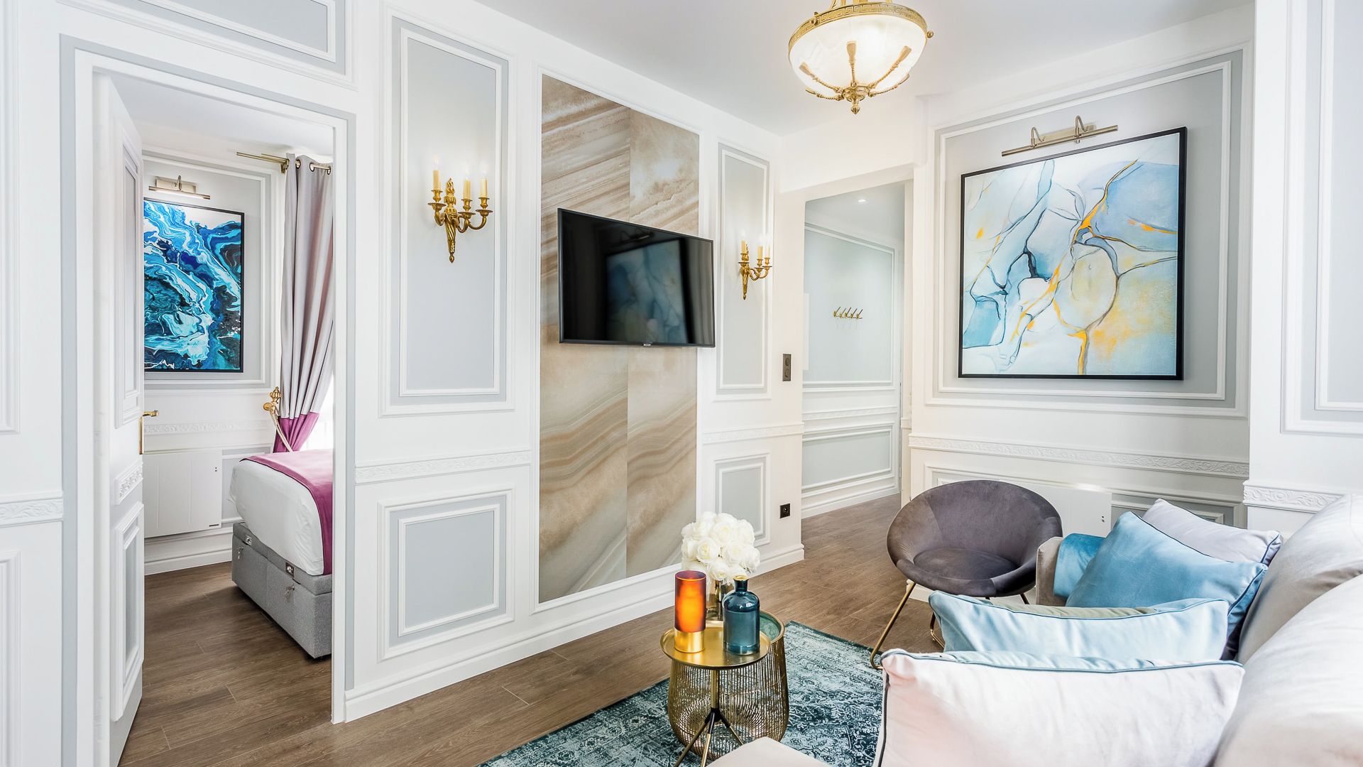 A spacious living room with a modern TV, a comfortable sofa, and a large abstract painting.