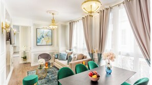 Una sala de estar moderna con un sofá, sillas, una mesa de comedor y una araña.
