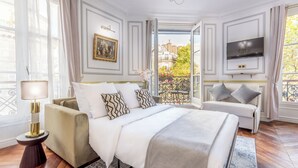 Une chambre d’hôtel avec un lit, un canapé, une télévision et un balcon donnant sur la ville.