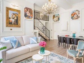 Ein geräumiges Wohnzimmer mit einer Couch, einem Essbereich mit Stühlen, einer Treppe und Kunstwerken an den Wänden.